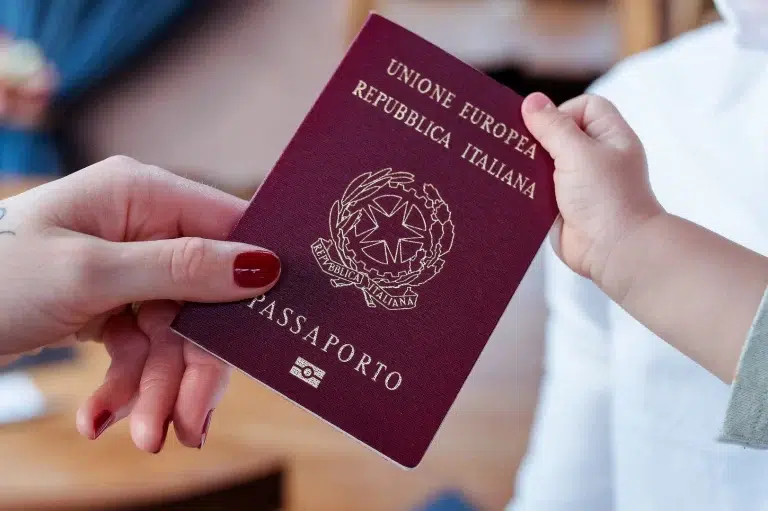 Passaporte italiano sendo segurado por uma mão adulta e de criança
